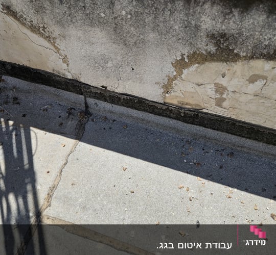 סימני רטיבות וקילופי טיח בקיר מעקה בגג או מרפסת
